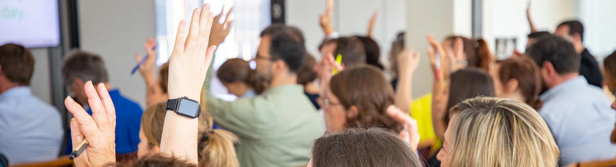 Participants at a WayAhead Workplaces meeting raising their hands in response to the speaker