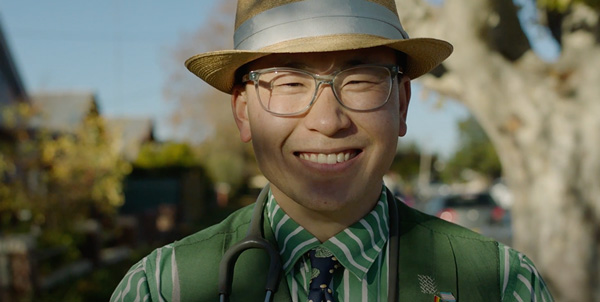 Dr Ho wearing a striking green tailored suit that he made himself, he is smiling